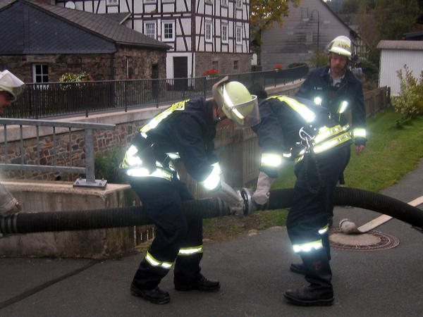 Drei Feuerwehrkameraden der Löschgruppe Elsoff im Einsatz, sie verbinden zwei Schläuche