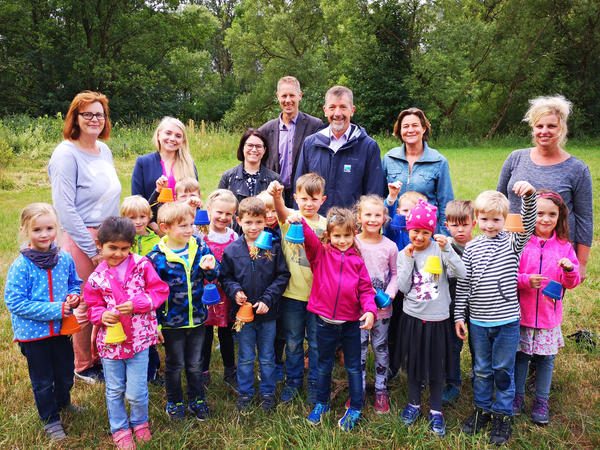 Bild vergrößern: Bürgermeister Bernd Fuhrmann und 1. Beigeordneter Volker Sonneborn stehen gemeinsam mit den Kindern und Erziehern des Familienzentrums "Blauland" auf der Wiese des Obst- und Gartenbauvereins in Raumland.