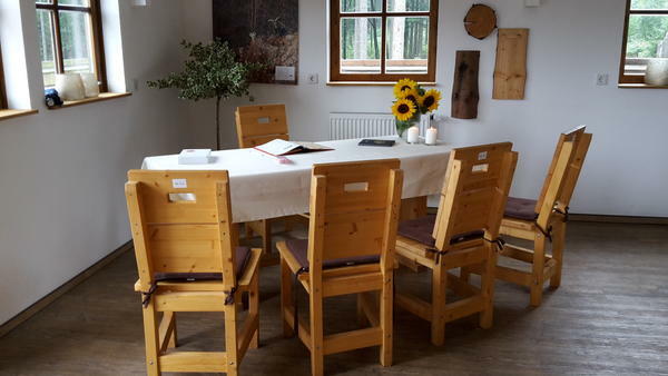 Bild vergrößern: Innenansicht Wisenthütte. Tisch mit weißer Tischdecke und Dekoration aus Sonnenblumen und Kerzen.