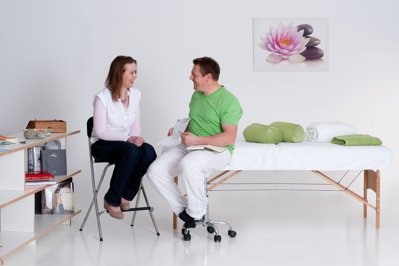 Bild vergrößern: Ein Therapeut berät eine junge Frau in einem hell gestalten Behandlungsraum.