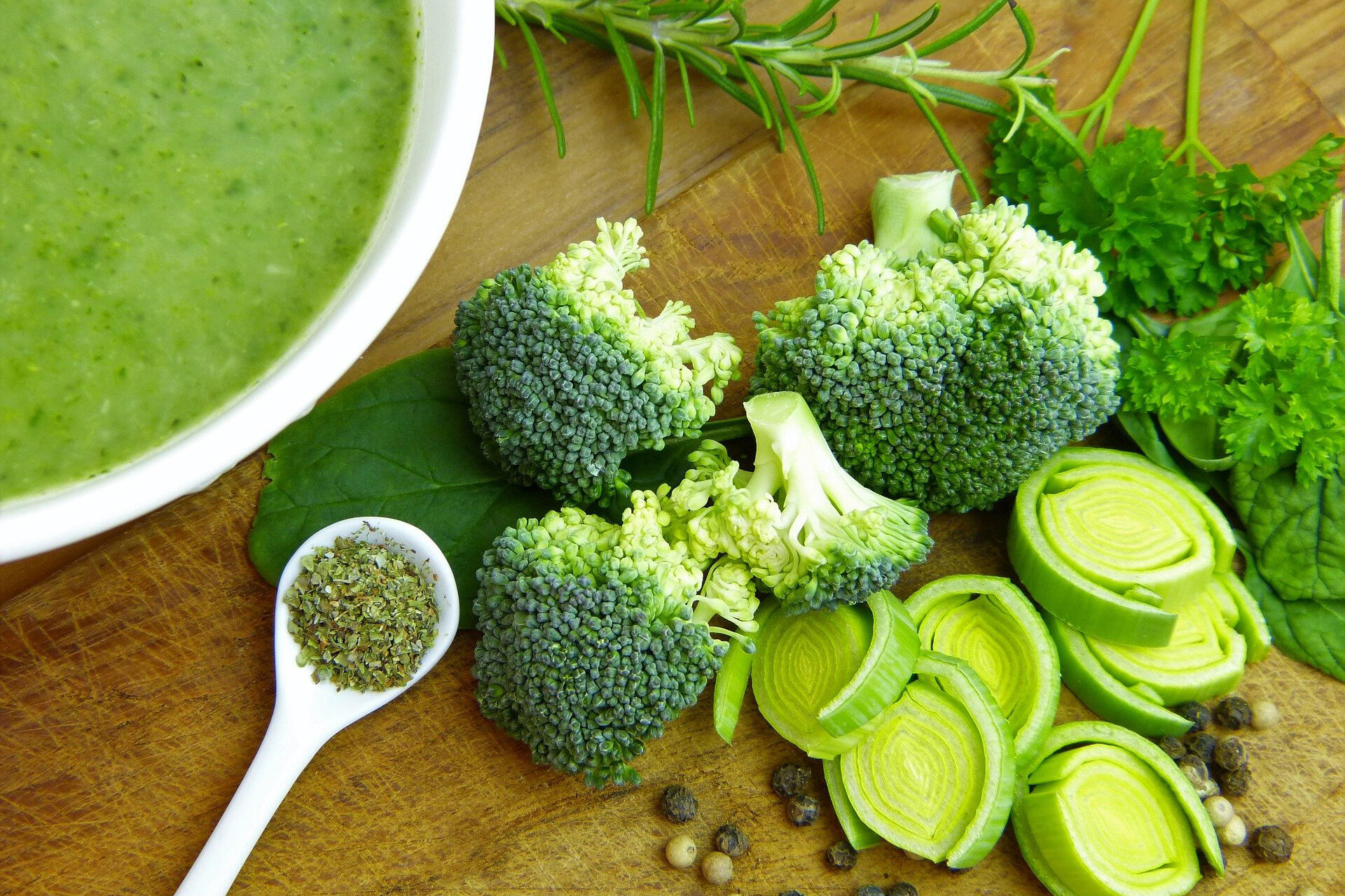 Bild vergrößern: Auf dem Tisch befindet sich grünes Gemüse (Brokkoli, Lauch, Salbei und Petersilie) und eine Suppentasse.