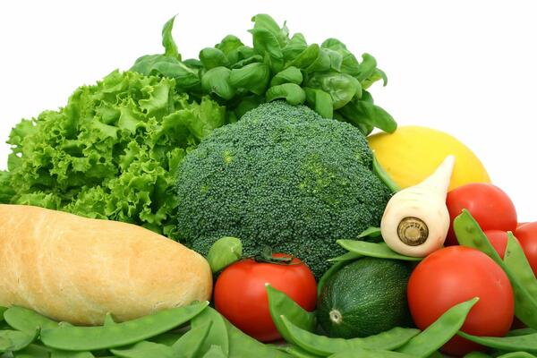 Bild vergrößern: m Bild sieht man frisches Gemüse. Im Vordergrund liegen eine Süßkartoffel, Tomaten, eine Zucchini, Pastinaken, gelbe Paprika, grünen Brokkoli, grünen Salat und grünes Basilikum.