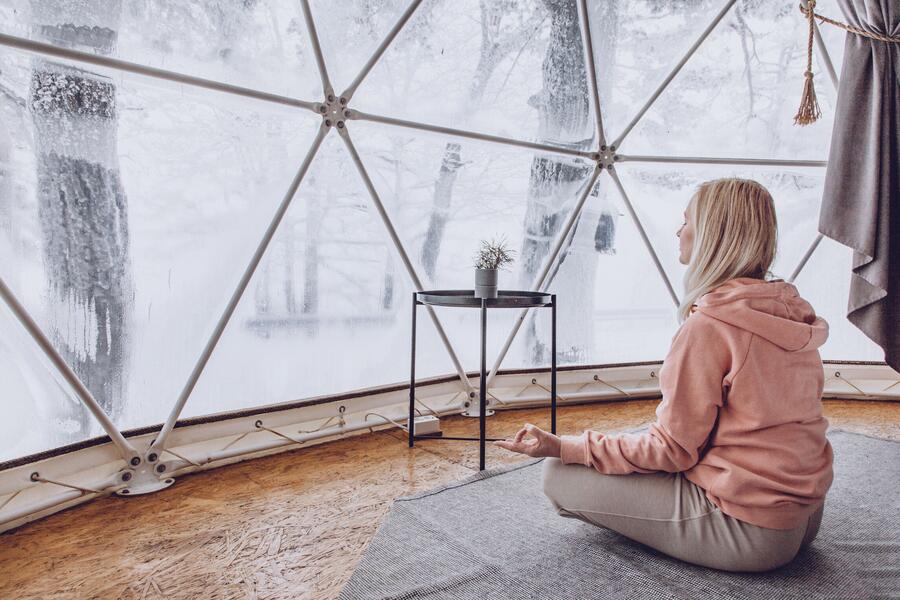 Bild vergrößern: Im Bild sieht man eine junge Frau in einer sitzenden YOGA Position, die sich in Achtsamkeit in Form einer Meditation übt.