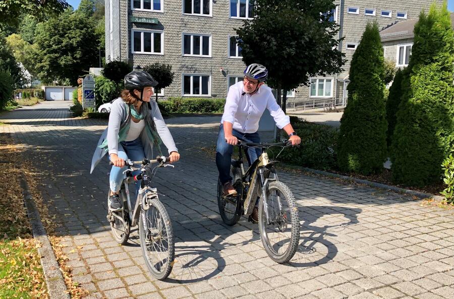 Bild vergrößern: Im Bild sieht man Jessica Durstewitz, Angestellte der Stadt Bad Berleburg und den Bürgermeister Bernd Fuhrmann auf dem Fahrrad unterwegs vor dem Rathaus Bad Berleburg.