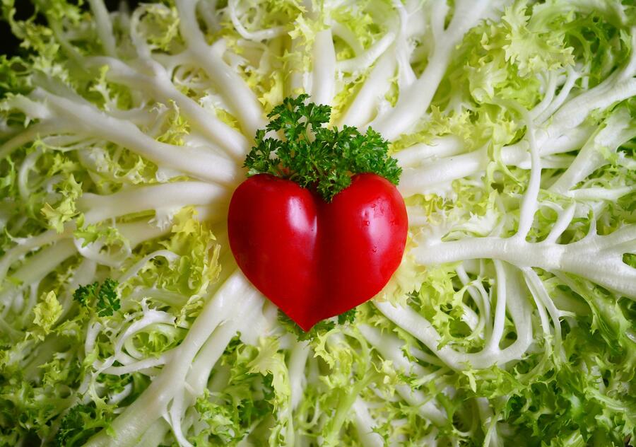 Bild vergrößern: Im Bild sieht man im Hintergrund einen grünen Salat und in der Mitte liegt als Herz geformt eine Paprika mit Petersilie verziert.