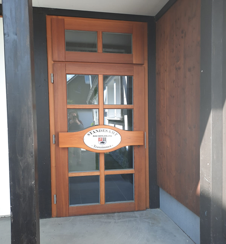 Bild vergrößern: Hier ist eine braune Holztür mit Scheiben  und dem Schild Standesamt Bad Berleburg Trauzimmer zu sehen. In der MItte des Schildes ist das Wappen der Stadt Bad Berleburg..