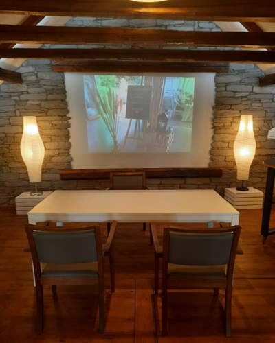 Bild vergrößern: Auf dem Bild ist der Traurbereich mit einem weißen Tisch und den 2 Stühlen für das Brautpaar zu sehen. Links und rechts stehen jeweils 2 Lampen.