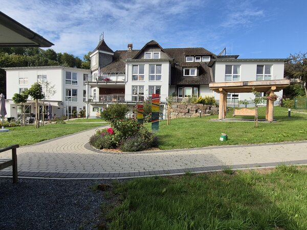 Bild vergr&ouml;&szlig;ern: Im Bild sieht man das Geb&auml;ude der Haus Ederh&ouml;he, man schaut auf den Eingangsbereich mit mehreren Balkonen und einer kleinen Wiese neben dem Eingang.