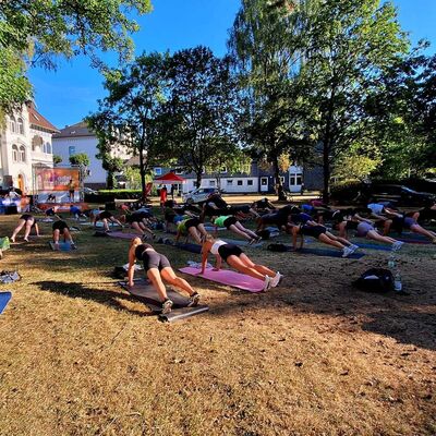 Bild vergr&ouml;&szlig;ern: Im Bild sieht man die Sportlerinnen und Sportler von hinten aufgenommen in einer kraftvollen St&uuml;tzposition in der Plank.