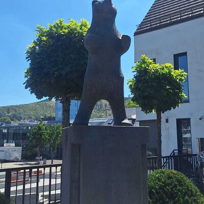 Bild vergr&ouml;&szlig;ern: Man schaut direkt auf die Statue, das Symbol der Stadt Bad Berleburg der B&auml;r. Im Hintergrund sieht man noch einen kleinen Teil des Marktplatzes und auf der rechten Seite angrenzend ein Wohnhaus.