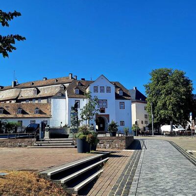 Bild vergr&ouml;&szlig;ern: Man schaut in der Mitte des Bildes direkt auf den Goetheplatz. Im Hintergrund sieht man ein Teilbereich von Schlo&szlig; Bad Berleburg. Auf der rechten und linken Seite sieht man die angrenzenden H&auml;user auf dem Goetheplatz.