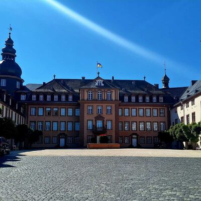 Bild vergr&ouml;&szlig;ern: Man schaut von der Eingangsforte direkt auf Schloss Bad Berleburg. Im Hintergrund einen strahlend blauen Himmel mit einem Sonnenstrahl direkt &uuml;ber dem Schloss.