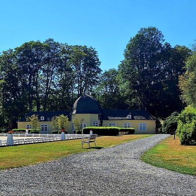 Bild vergr&ouml;&szlig;ern: Im Hintergrund sieht man die Orangerie Bad Berleburg. Das Geb&auml;ude ist in gelb verputzt und die Fenster sind in wei&szlig; abgesetzt. Im Vordergrund sieht man auf der linken Seite ein Teil einer Pferdekoppel.
