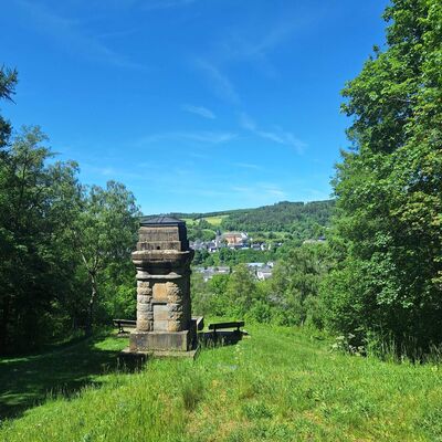 Bild vergr&ouml;&szlig;ern: Man schaut direkt auf die Bismarcks&auml;ule und den kleinen Vorplatz mit zwei B&auml;nken. Im Hintergrund schaut man auf Teile der Oberstadt und das Schloss Berleburg.