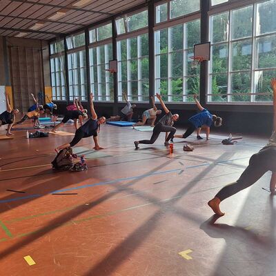 Bild vergr&ouml;&szlig;ern: Im Bild sieht man eine gro&szlig;e Gruppe an Sportlerinnen und Sportlern. Sie sind alle in einer St&uuml;tzposition am Boden linke Hand abgest&uuml;tzt und der rechte Arm gerade nach oben ausgestreckt.